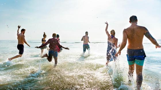 Ungdom hopper i havet en fin sommerdag.