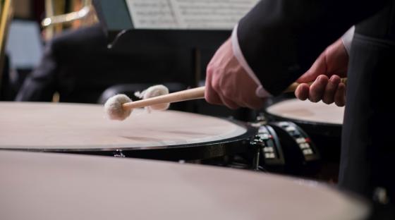 Hender holdende på vatterte trommestikker som spiller på timbales eller timpani, en type trommeinstrument. 